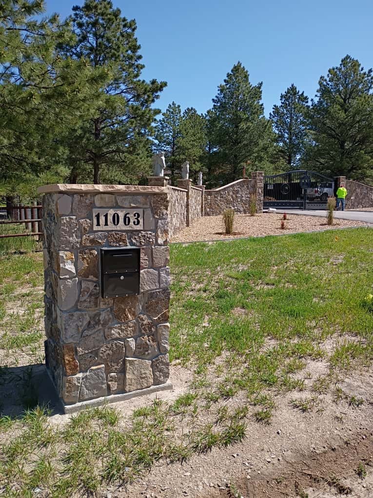 A custom-built stone masonry mailbox pillar with an integrated black metal box